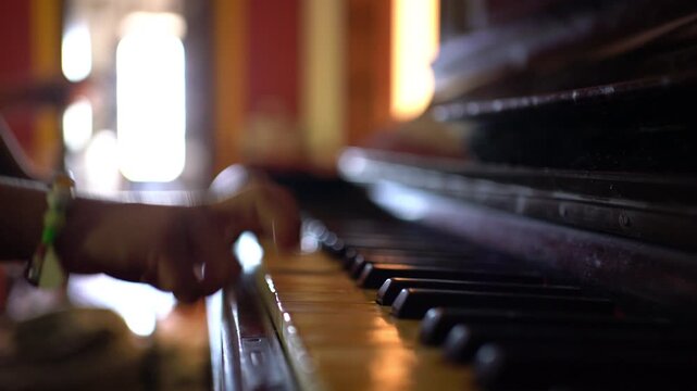 A close-up shows a boy's fingers playing the keys of a very old, vintage piano