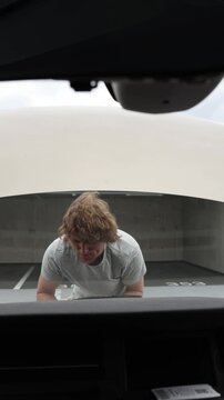 Vertical screen driver opens the hood and investigates the engine compartment to determine the cause of the car breakdown while searching carefully for a mechanical fault