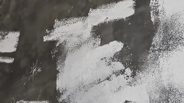 a hand using a paint roller to apply white primer on a dark textured concrete wall, ideal for home renovation, interior design, DIY repair, wall finishing, and construction concepts.