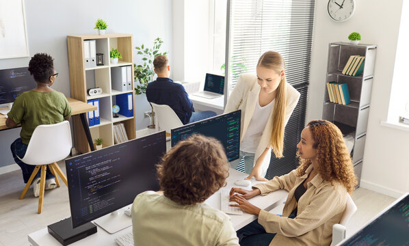 Developers programmers team coding collaboration in office. They discuss software on laptops and monitors, promote teamwork, and refine code. Modern team collaboration software concept.