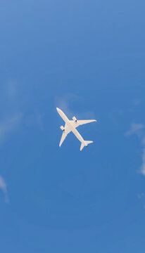 A white commercial airplane flying overhead against a clear blue sky