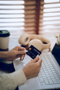 Woman using a laptop while holding a credit card, representing online shopping, digital payment, e-commerce and secure financial transactions.