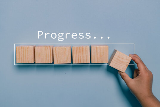 Hand putting wooden cube on virtual infographic rectangle block with progress wording. Job progressive concept.