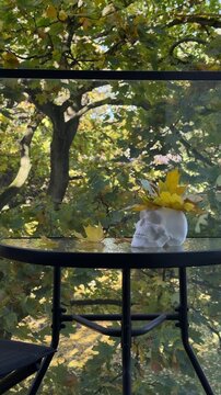 Skull vase with fallen maple leaves on balcony bistro table, reflecting seasonal decorating trends, small space living and foraged natural decor