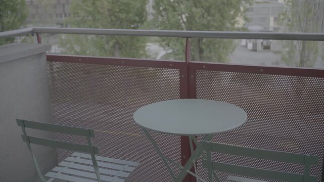 Green metal bistro table and chairs on a balcony with outdoor view