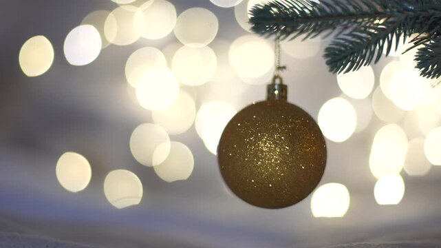 Golden Christmas Ball on Christmas Tree with light bokeh on background. New Year's festive Christmas balls decorate the Christmas tree. New Year's Eve