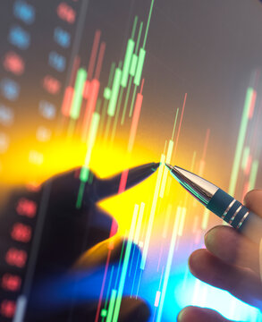 Male share price analyst pinpoints financial data on a screen