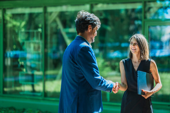 A businessman and a businesswoman shake hands outside the office