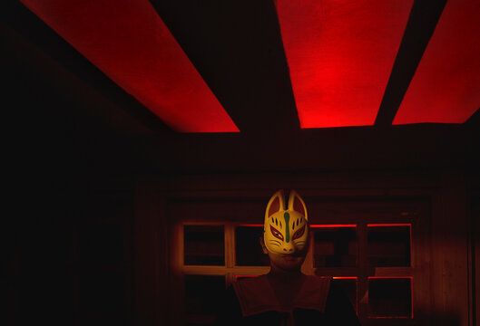 Japanese fox mask in dark room with eerie red neon lighting