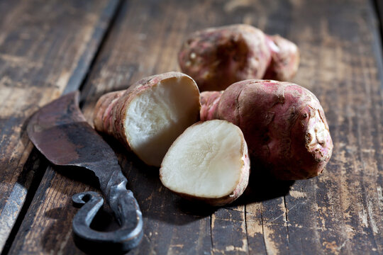 Whole and sliced Jerusalem artichoke and an old knife on wood