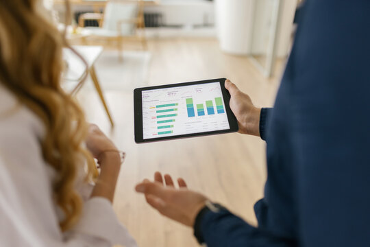 Male consultant explaining financial data on a tablet to a woman