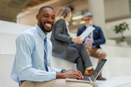 Smiling businessman works on laptop while sitting on office stairs