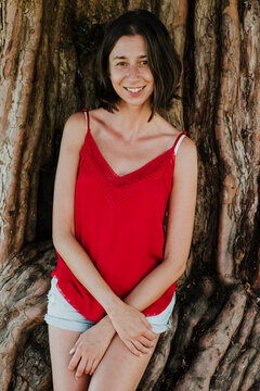 Smiling woman sits by an ancient tree in Asturias during summer