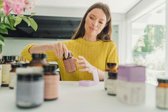 Woman holds supplement bottle for gut health at home
