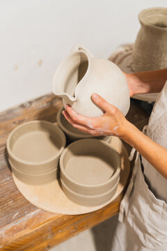 Female artisan holding a handmade clay pitcher in a pottery studio