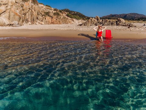 Woman enjoys summer vacation on a beach chair in the turquoise water