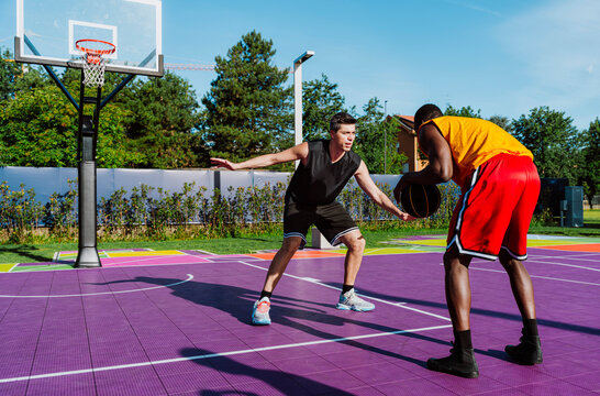 A man plays defense during a streetball game on an outdoor court