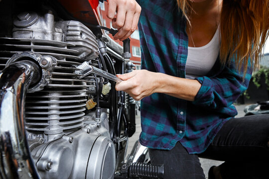 Close-up of young woman working on motorcycle