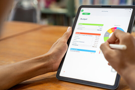 Extreme closeup of tablet screen showing personal monthly budget planner application with colorful pie chart and expense tracking list