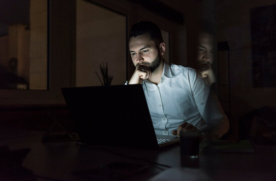 Businessman working on laptop in office at night