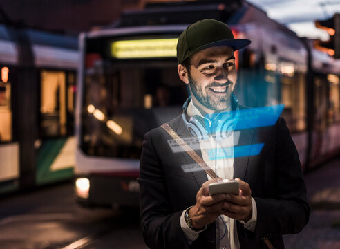 Young man outdoors at dusk with text emerging from smartphone