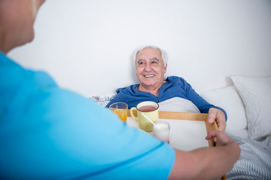 Gereatric nurse bringing tea at patient's bed
