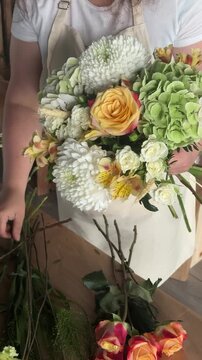 Florist assembling mixed bouquet at studio worktable, reflecting small business craft, artisanal skills and local flower shop economy