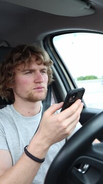 Vertical screen driver looks down at a smartphone while traveling in a moving car taking attention away from changing traffic conditions and creating a unsafe road hazard