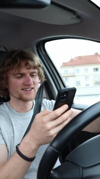 Vertical screen motorist smiles at content on a smartphone and takes attention away from the road while the moving vehicle creates an extremely dangerous safety situation
