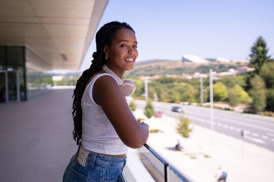 A young African American woman smiles outdoors on a balcony