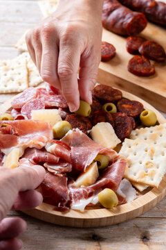 People sharing Spanish tapas with serrano ham, chorizo and red wine on wooden table
