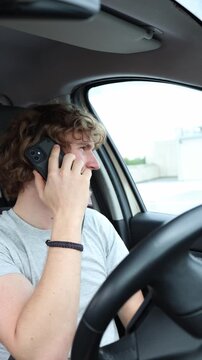 Vertical screen driver speaks on a handheld phone behind the wheel breaking traffic rules and creating a serious safety hazard while operating a car on a busy public roadvertical 