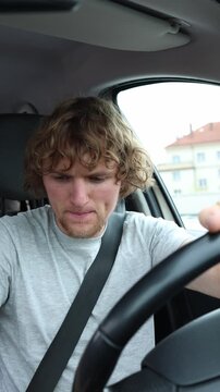 Vertical screen driver sits inside a parked car fastens the seatbelt and prepares for a safe journey showing responsible behavior before pulling away and entering traffic