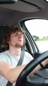 Vertical screen tired driver drives to work as he struggles with exhaustion behind the wheel and moves through busy city traffic during a stressful early morning commute