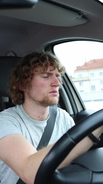 Vertical screen exhausted driver nearly falls asleep while driving as the car continues through traffic creating a major accident risk during a lengthy and tiring journey