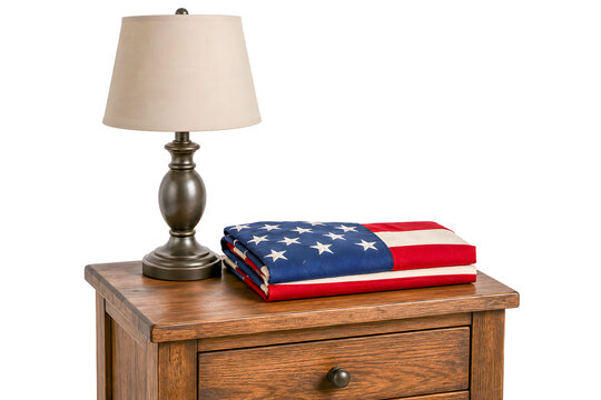 Folded American flag on wooden bedside table with lamp  