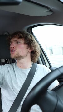Vertical screen aggressive driver threatens another motorist from behind the wheel while moving through busy city traffic during a heated and dangerous road confrontation