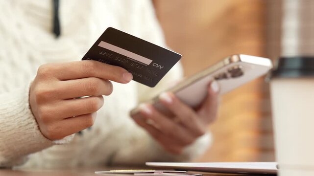 Woman holding a credit card and smartphone, representing online shopping, digital payment, e-commerce, mobile banking and cashless transactions.