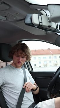Vertical screen responsible driver fastens a seat belt inside a stationary car before starting the journey following safety rules and demonstrating careful driving habits