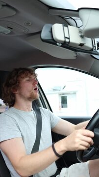 Vertical screen inexperienced driver keeps both hands on the steering wheel and slowly turns the moving car while navigating a city street with limited driving experience