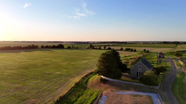 A scenic drone shot capturing the historic former island of Schokland in the Netherlands on a bright, sunny day. Rotating shot of house with lighthouse behind it.