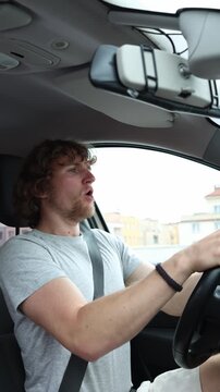 Vertical screen novice driver grips the steering wheel and carefully drives through city traffic showing concentration uncertainty and limited experience behind the wheel