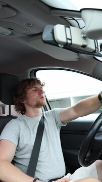 Vertical screen driver sits behind the wheel with a seat belt fastened and calmly controls the moving car while traveling through the city during a regular daily journey