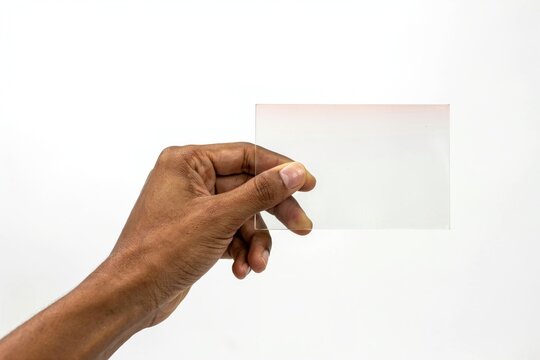 Person holding a clear rectangular glass filter isolated on white background