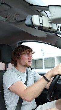 Vertical screen sleepy driver keeps his hands on the wheel while driving through the city with heavy eyelids low energy and reduced concentration during a monotonous trip
