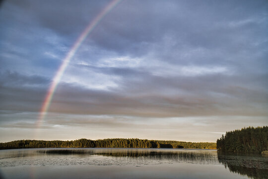 Luminous Rainbow Over Calm Forest Lake