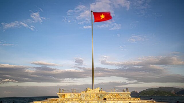 Nha Trang city center in Vietnam during the evening, featuring a large Vietnamese national flag waving on a central city square.