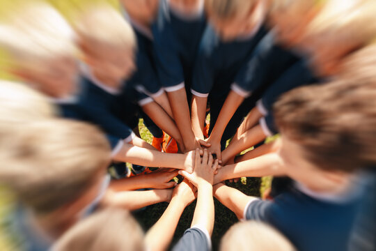 Youth Sports Team Stacking Hands in Center Circle Before Match - Children Football Team Unity, Togetherness, and Motivation Motion Blur Shot