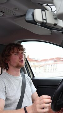 Vertical screen angry young driver argues with nearby motorists while driving through city traffic and makes rude gestures expressing road rage frustration and aggression