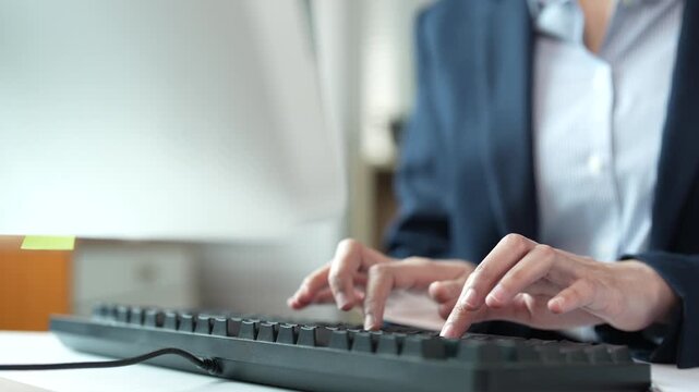 Professional businesswoman hands typing on a computer keyboard, corporate employee working at a desk, sending emails and writing documents in a modern office environment